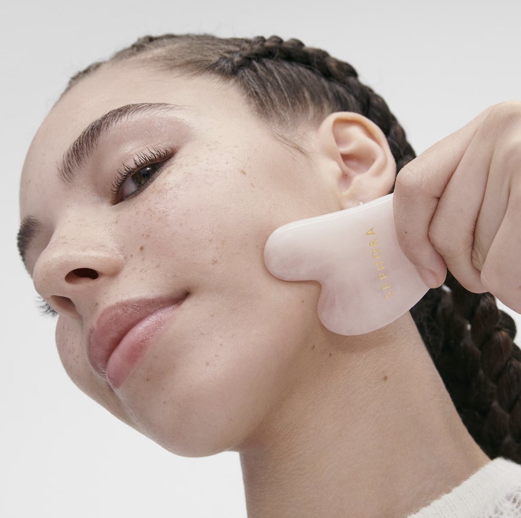Gua sha al quarzo rosa usato lungo lo zigomo